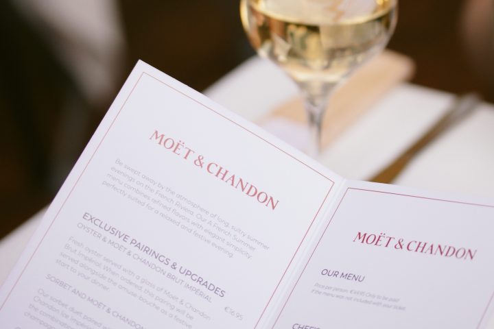 Menu with Moët & Chandon branding next to a glass of white wine.