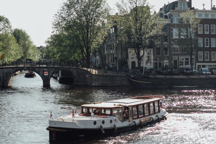 Boat on canal with bridge and buildings in the background.