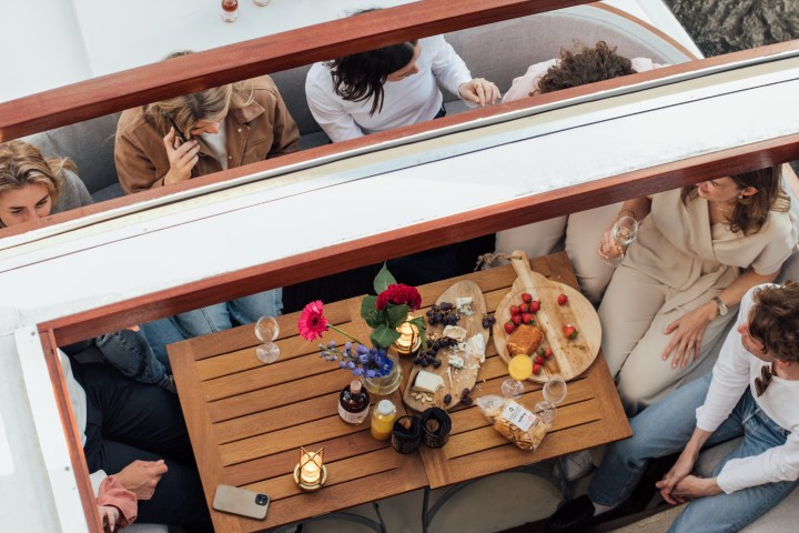 Aerial view of people sitting around a table with food and drinks on a boat.