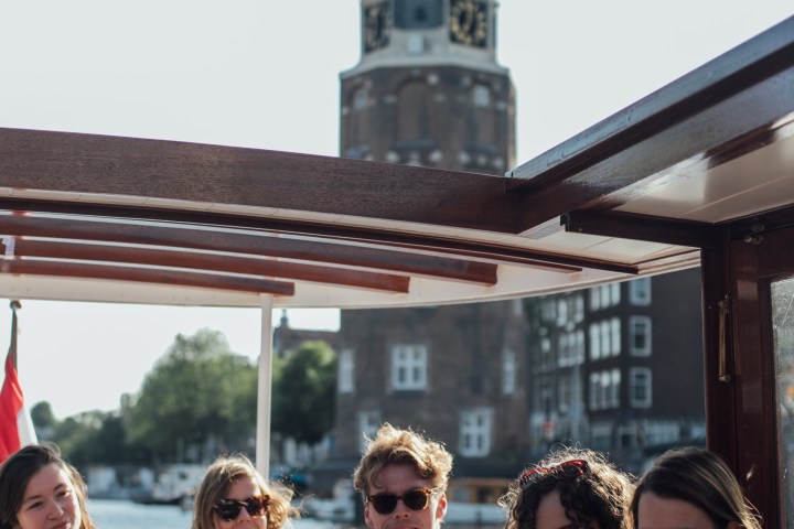 Group of people sitting on a boat with a historic tower in the background.