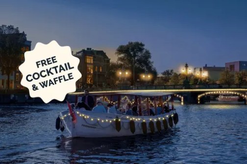 Evening boat cruise with string lights offers free cocktail and waffle, city lights in the background.